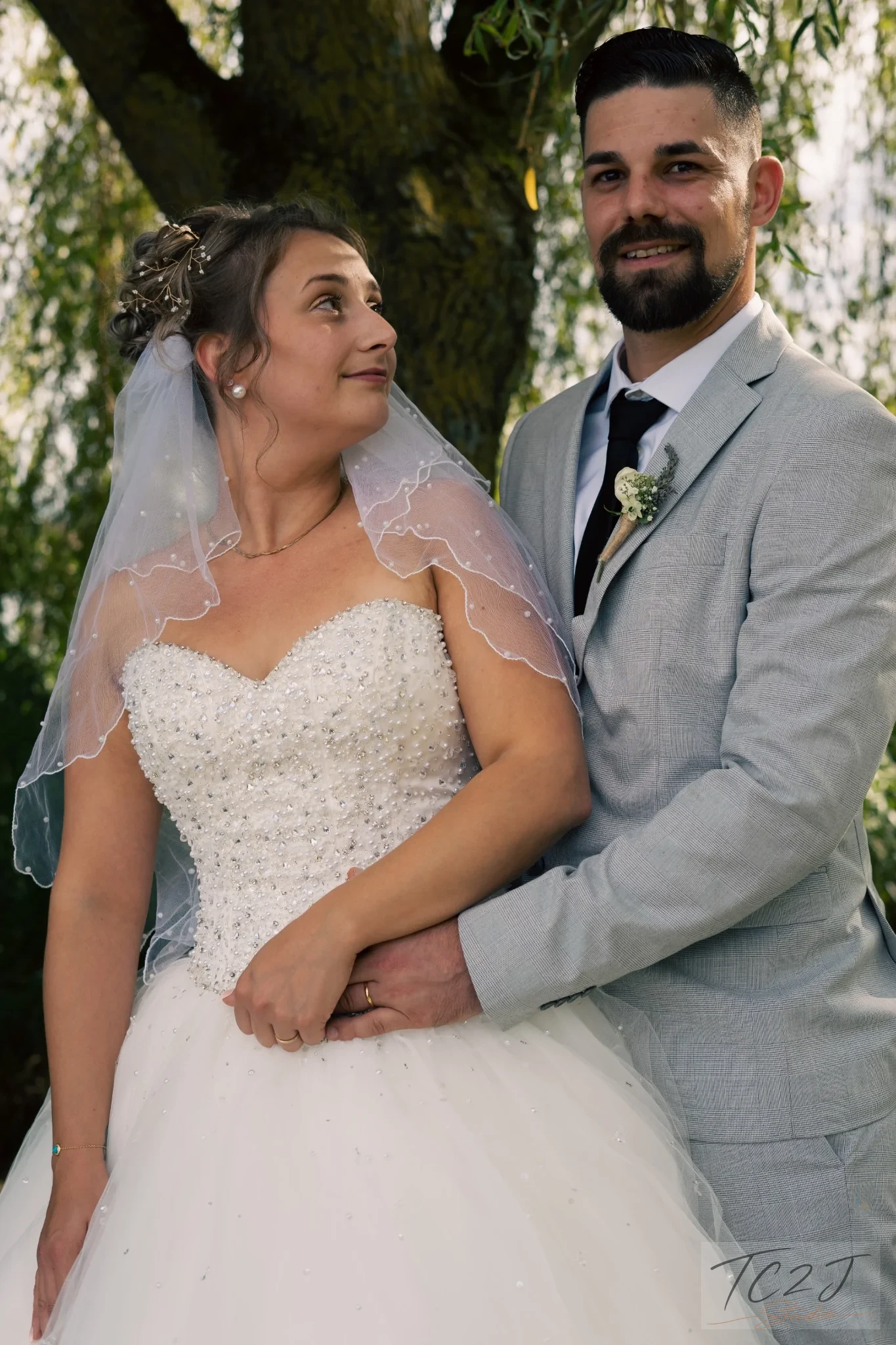Couple de mariés posé sous un arbre